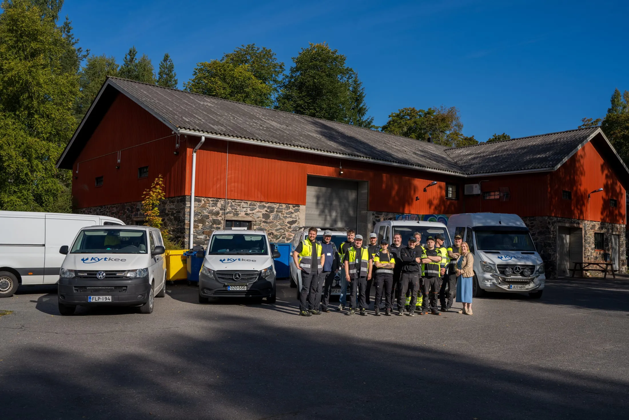 Kytkeen henkilökunta yrityksen pakettiautojen edessä