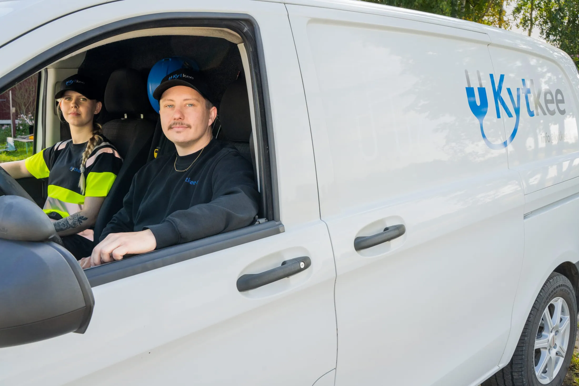 Kaksi Kytkeen asentajaa yrityksen pakettiauton ohjaamossa