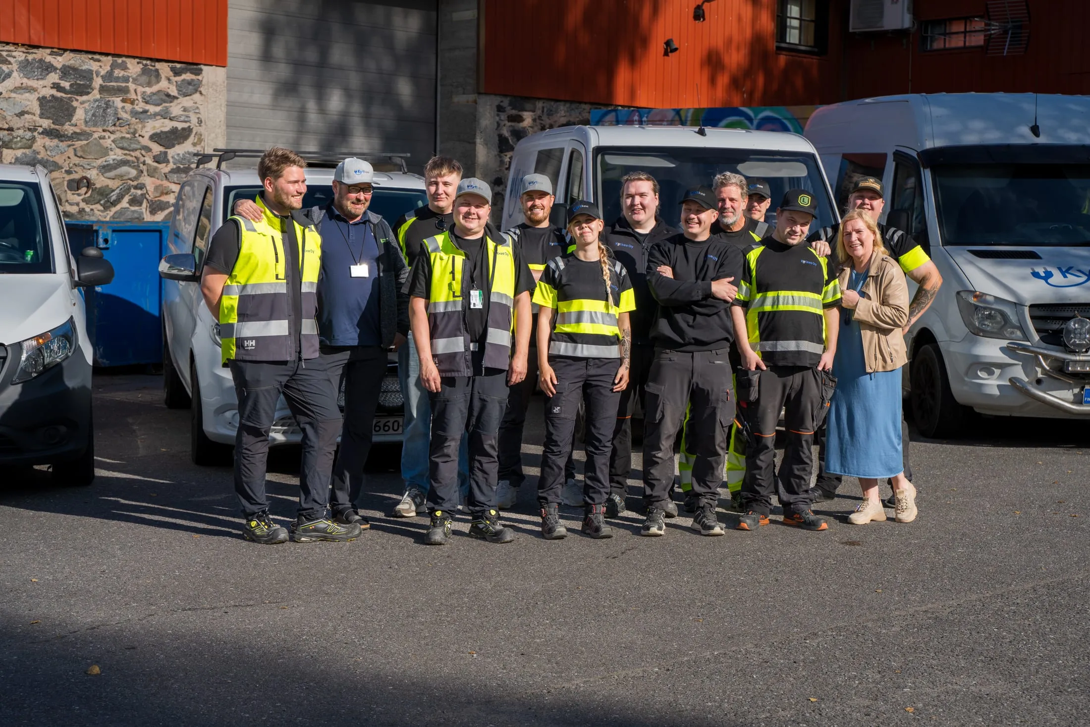 Kytkee Oy:n henkilöstö ryhmäkuvassa pakettiautojen edessä